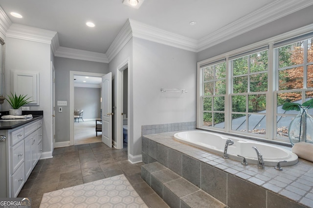 bathroom with tiled tub, crown molding, vanity, and toilet