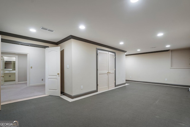 basement with crown molding and dark carpet