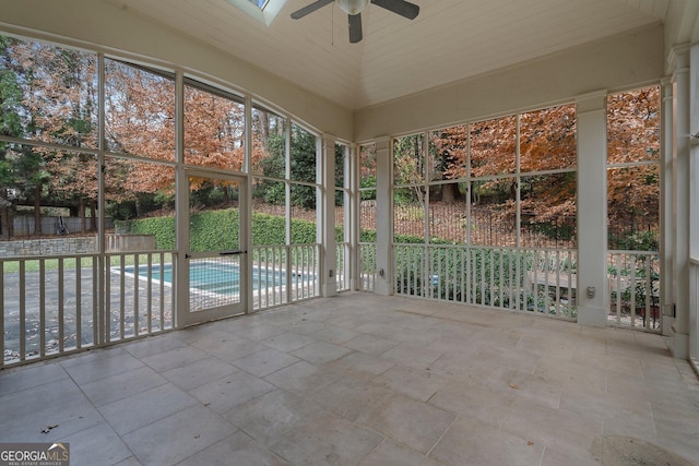 unfurnished sunroom featuring vaulted ceiling with skylight, ceiling fan, and wooden ceiling