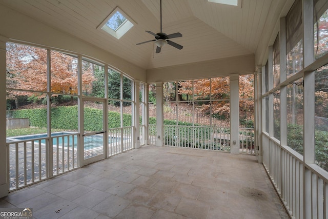 unfurnished sunroom with ceiling fan, wooden ceiling, and vaulted ceiling with skylight