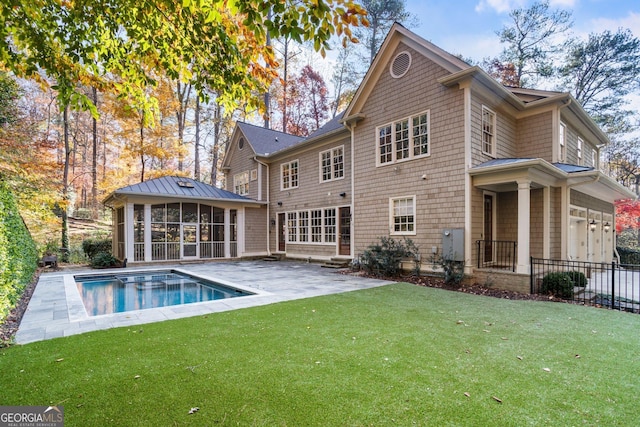 back of house featuring a lawn, a sunroom, a garage, a fenced in pool, and a patio area