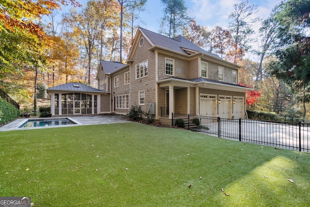 rear view of house featuring a sunroom, a yard, and a garage