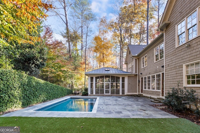 view of pool featuring a lawn, a patio area, and a sunroom