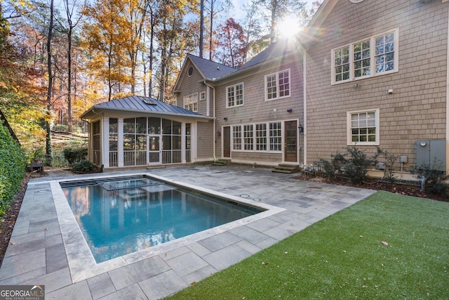 back of house with a sunroom, a patio, and a lawn