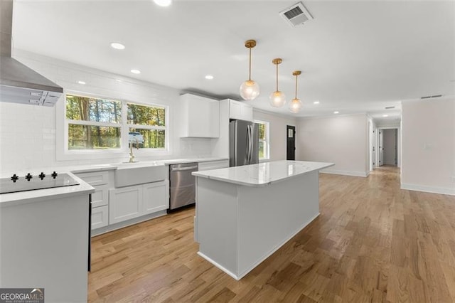 kitchen featuring white cabinets, stainless steel appliances, pendant lighting, and light hardwood / wood-style flooring