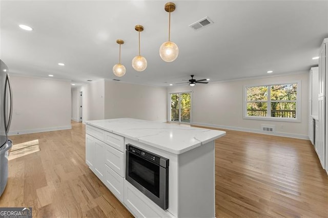 kitchen featuring white cabinetry, light wood-type flooring, pendant lighting, and a center island