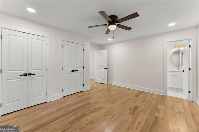 unfurnished bedroom featuring light hardwood / wood-style floors, ceiling fan, multiple closets, and ensuite bathroom