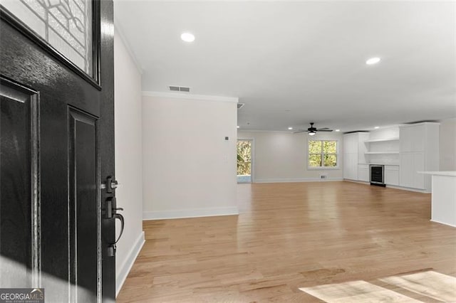 foyer featuring ornamental molding, light wood-type flooring, and ceiling fan