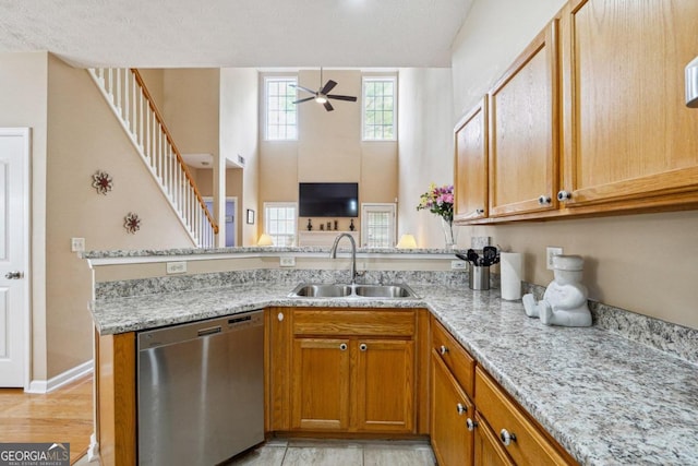 kitchen with sink, kitchen peninsula, a textured ceiling, light wood-type flooring, and dishwasher