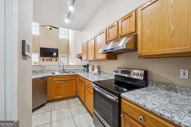 kitchen with stainless steel appliances, light stone counters, a towering ceiling, sink, and light tile patterned floors