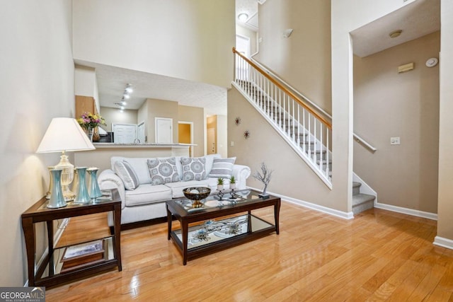 living room with a towering ceiling and light hardwood / wood-style flooring