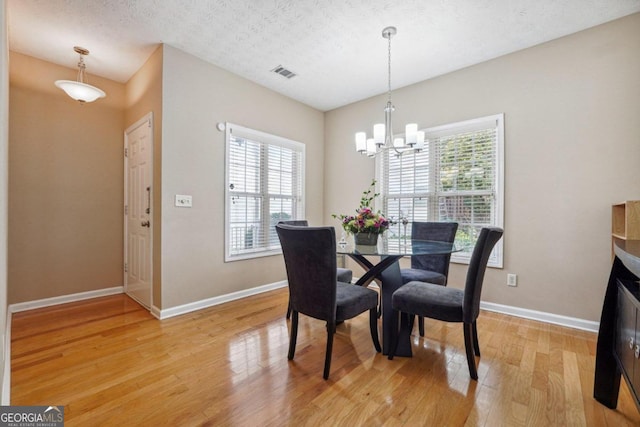 dining space featuring a chandelier, a textured ceiling, and light hardwood / wood-style flooring