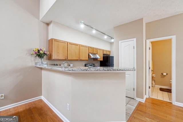 kitchen featuring black refrigerator, a textured ceiling, light wood-type flooring, and kitchen peninsula