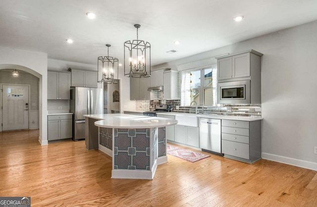 kitchen with stainless steel appliances, gray cabinetry, tasteful backsplash, and a center island