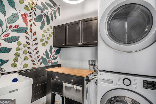 laundry area with stacked washing maching and dryer and cabinets