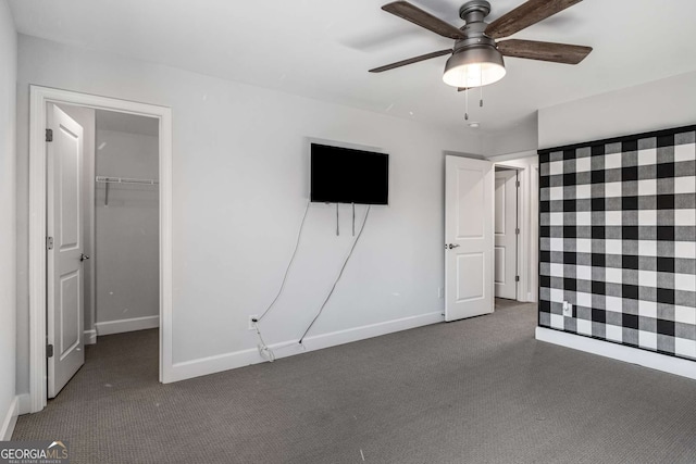 unfurnished bedroom featuring ceiling fan, a closet, a spacious closet, and dark colored carpet