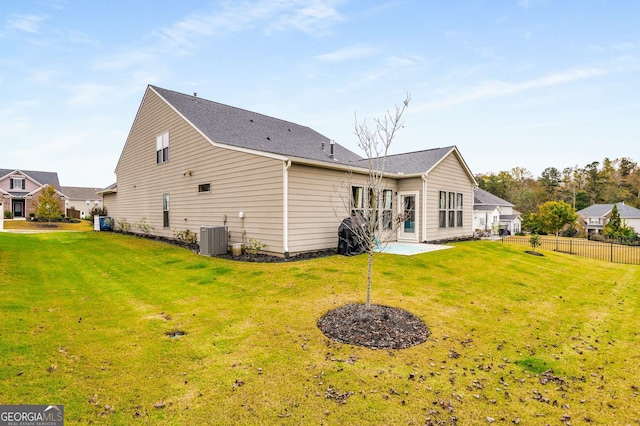 rear view of property with central AC and a yard