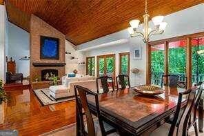 dining area featuring wooden ceiling, a large fireplace, vaulted ceiling, and a notable chandelier