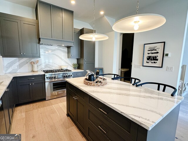 kitchen with light stone countertops, a kitchen island, light wood finished floors, and high end stove