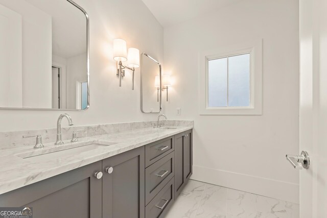 bathroom with a sink, baseboards, marble finish floor, and double vanity