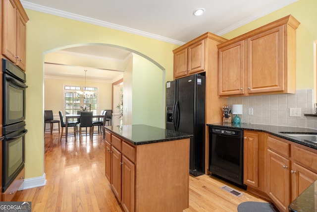 kitchen with dark stone counters, black appliances, crown molding, pendant lighting, and light hardwood / wood-style flooring