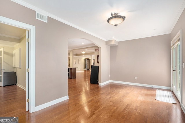 empty room with ornamental molding and hardwood / wood-style flooring