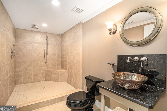 bathroom with toilet, vanity, a tile shower, and crown molding