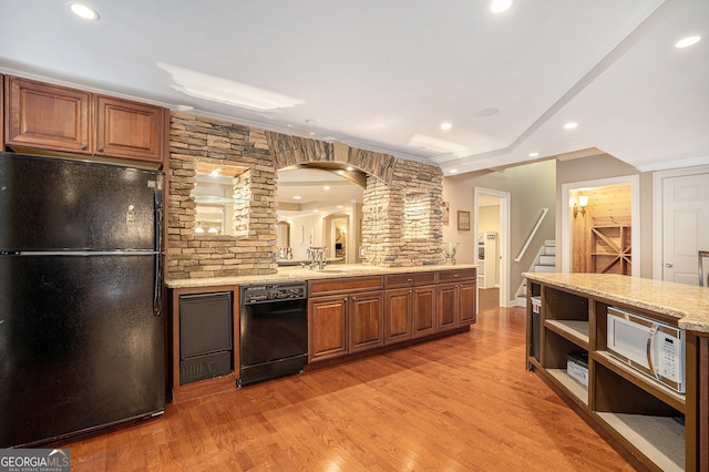 kitchen with black appliances, decorative backsplash, light stone counters, and light hardwood / wood-style floors