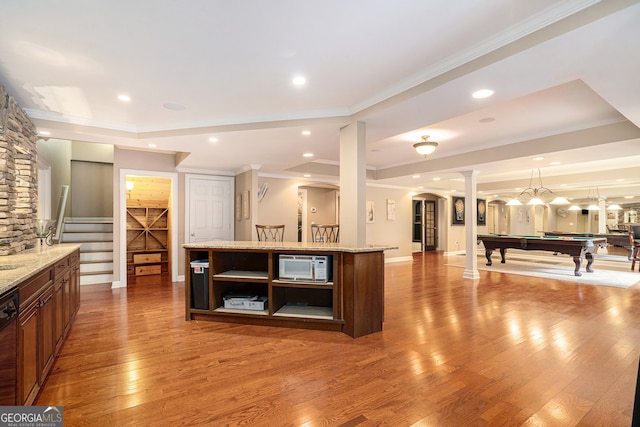 kitchen with pool table, light stone counters, wood-type flooring, and a center island