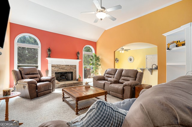 carpeted living room featuring a stone fireplace, a wealth of natural light, lofted ceiling, and ceiling fan