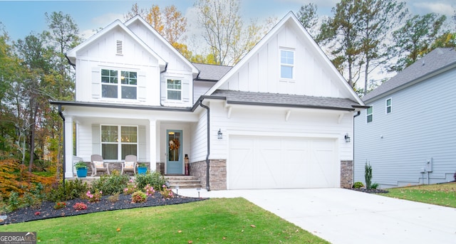 view of front of property featuring covered porch, a garage, and a front yard