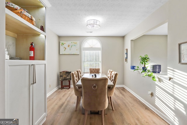 dining room with hardwood / wood-style floors and a textured ceiling