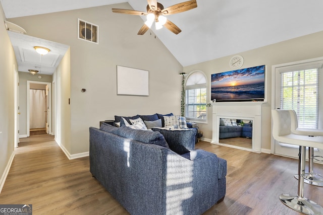 living room featuring ceiling fan, high vaulted ceiling, and hardwood / wood-style flooring