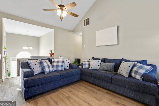 living room featuring ceiling fan with notable chandelier, hardwood / wood-style flooring, and high vaulted ceiling