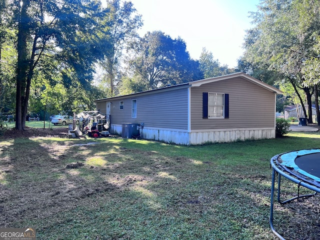 view of side of home with a yard and a trampoline