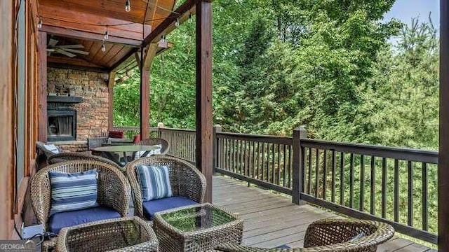 wooden terrace with an outdoor stone fireplace