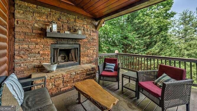 wooden terrace with an outdoor stone fireplace