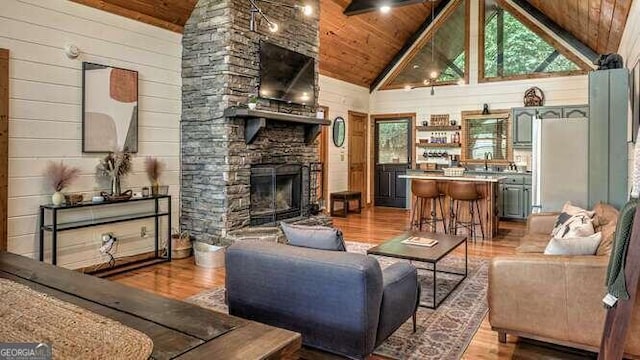 living room with a stone fireplace, high vaulted ceiling, light hardwood / wood-style flooring, and wood ceiling