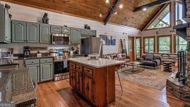 kitchen featuring stainless steel appliances, light wood-type flooring, high vaulted ceiling, wood ceiling, and wooden walls