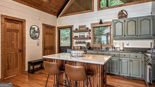 kitchen featuring wood ceiling, lofted ceiling, a center island, gray cabinetry, and light wood-type flooring