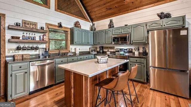 kitchen featuring stainless steel appliances, vaulted ceiling, sink, wooden ceiling, and a kitchen island