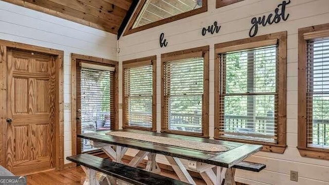 dining room with wooden ceiling, wood-type flooring, wooden walls, and vaulted ceiling