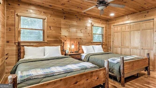 bedroom with light wood-type flooring, wooden walls, and multiple windows