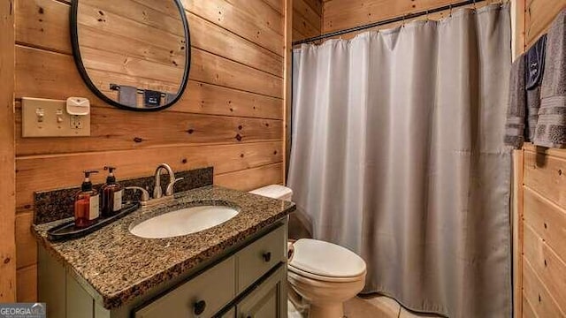 bathroom with curtained shower, vanity, wooden walls, and toilet