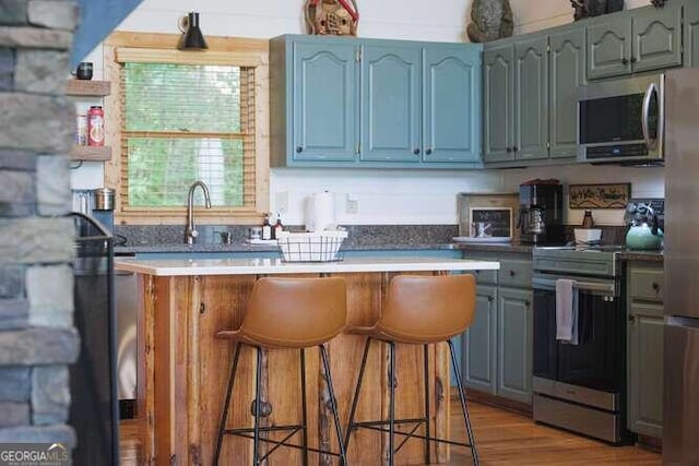 kitchen with stainless steel appliances, a breakfast bar area, sink, and light wood-type flooring