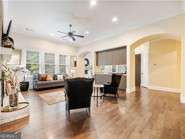 living area with light wood-style flooring, arched walkways, and baseboards