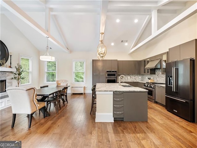 kitchen featuring gray cabinets, decorative backsplash, a sink, high quality appliances, and under cabinet range hood