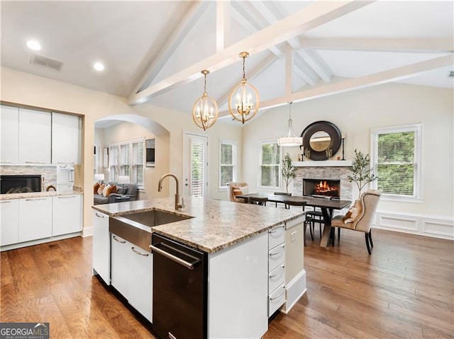 kitchen featuring black dishwasher, open floor plan, a fireplace, and a sink