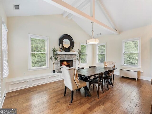 dining space with visible vents, a stone fireplace, and hardwood / wood-style flooring