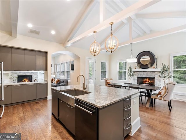 kitchen featuring dishwashing machine, a lit fireplace, open floor plan, and gray cabinetry